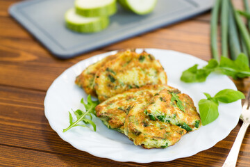 breakfast of zucchini fritters with green onions in a plate on a wooden table