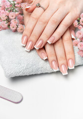 Woman showing her french manicure on a white towel