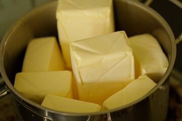 High-quality image of fresh butter cubes in a metal bowl, perfect for culinary websites or food blogs.