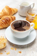 Steaming coffee, fresh croissants, and honey create a tempting breakfast scene
