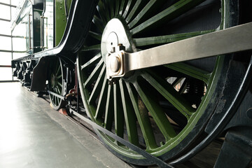 Detailed view of the main power wheel of an early 20th century steam powered British train seen within the confines of a railway museum on England.