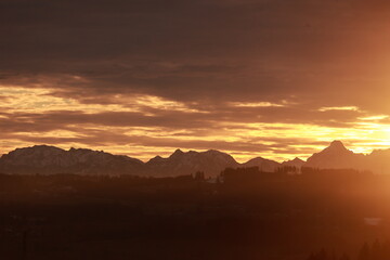 The sun is setting over a mountain range, casting a warm glow over the landscape