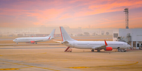 Commercial passenger airplane during taxi movement for take off, and another boarding passenger for flight early morning
