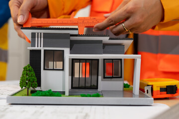 Person measuring modern house model with ruler on architectural plans