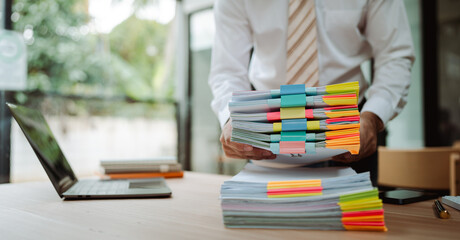 Portrait of businessman working with stack of documents to search for information and check...