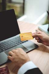 Close-up of a man entering credit card information on a laptop to complete a payment transaction....