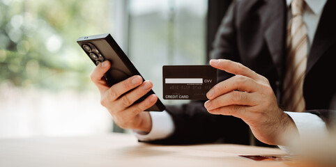 Close-up of a man filling in credit card information on a smartphone to complete a payment transaction. Online shopping, payment, login.
