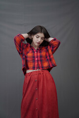 Confident Young Woman in Red Plaid Shirt and Long Buttoned Skirt Posing Indoors