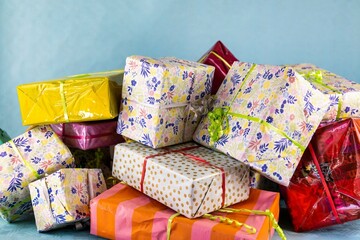 Colorful Stack of Gift Boxes on Blue Background
A festive arrangement of various gift boxes wrapped in colorful paper and decorated with ribbons, placed against a soft blue background. Perfect for the