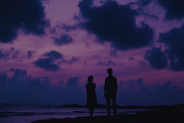 A silhouette of two people, a man and a woman, in the distance on a beach at sunset