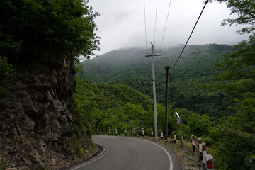 Turn of the road with incredible view of mountains and forest in fog, cloudy