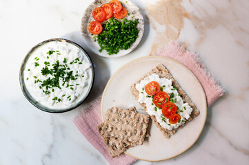Healthy breakfast concept with whole grain breast topped with cottage cheese and cherry tomato slices.