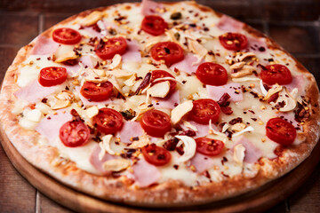 Pizza with ham, cherry tomatoes and mozzarella cheese. Wooden background. Soft focus. Close up.	