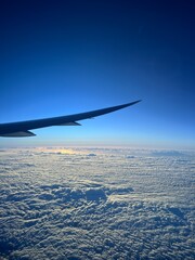 The view outside of a plane window of the plane wing and the island of O'ahu showing the impressive Hawaiian mountain range and city of Waikiki on a sunny day in summer.