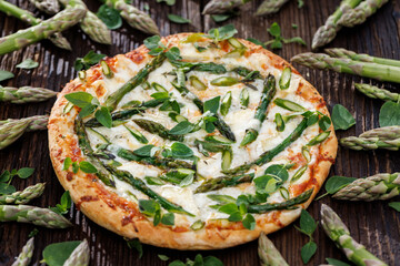 Green asparagus pizza sprinkled with fresh herbs, close-up view