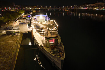 A barge converted into a bar in Lyon along the Rhône River at dusk.