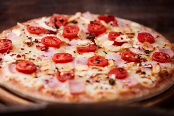 Pizza with ham, cherry tomatoes and mozzarella cheese. Wooden background. Soft focus. Close up.	
