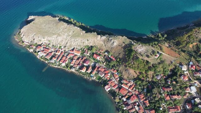 Forward drone shot over Lin village in Pogradec, Albania, revealing red-roof houses along Lake Ohrid, a coastal peninsula, and the site of Europe&rsquo;s most ancient known settlement.