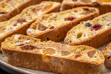 Italian Almond Biscotti biscuits in a rustic home made pottery bowl. Studded with almonds and cranberries, these twice-baked treats are aromatic and inviting. Ideal.