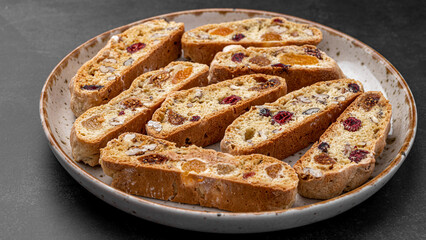 Italian Almond Biscotti biscuits in a rustic home made pottery bowl. Studded with almonds and cranberries, these twice-baked treats are aromatic and inviting. Ideal.