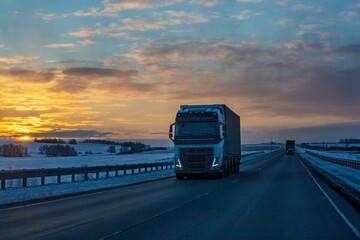 A truck is driving along the highway outside the city in winter