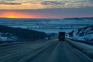 A truck is driving along the highway outside the city in winter