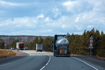 A tanker truck drives along a highway outside the city