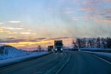 A truck is driving along the highway outside the city in winter