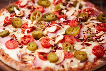 Pizza with ham, cherry tomatoes and mozzarella cheese. Wooden background. Soft focus. Close up.	