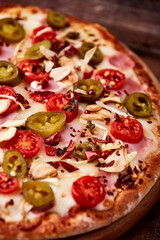 Pizza with ham, cherry tomatoes and mozzarella cheese. Wooden background. Soft focus. Close up	