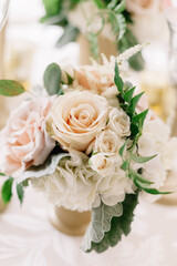 Floral arrangement featuring soft pink and white roses with greenery in a decorative vase at an elegant event