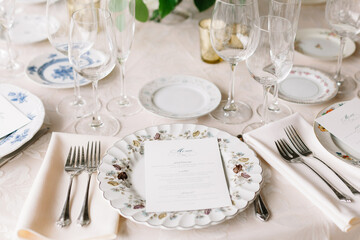 Elegant dining setup with floral plates and crystal glassware at a festive event in a beautifully decorated venue