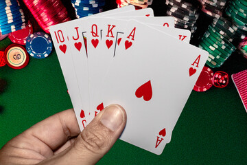 Royal flush in hand against a casino background.