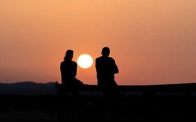 Silueta de una pareja al atardecer con el sol entre ambos