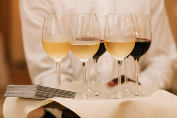 Server presents assorted wine glasses on a tray during a formal event in an elegant setting