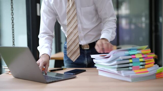 Businessman hands working in stacks documents of paper files, searching information on desk office, Accounting budget report file, check working for arranging unfinished of paperwork on busy office