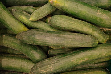 Close-up of a pile of organic cucumbers with natural imperfections and earthy textures. Ideal for fresh produce, farming, healthy eating, or sustainability themes with a rustic, natural aesthetic.