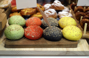 mini panes brioche de colores y sabores variados con semillas y sésamo en una tabla de madera en la cocina