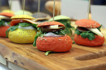 pincho de mini hamburguesas de pan brioche especial de colores con ingredientes en una tabla de...