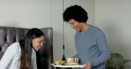 Triggered by breakfast tray entering, diverse couple sharing coffee and croissant ritual in bedroom - Powered by Adobe