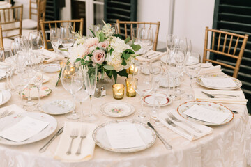 Elegant table setting with floral centerpiece for a wedding reception in a bright venue