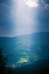 Sunlight illuminates a mountain valley with human huts