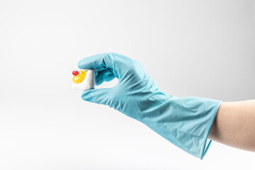 hand in a blue rubber glove, holds a dishwasher tablet