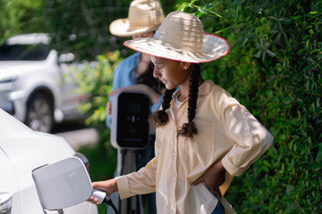Two sisters charging an electric car, eco-friendly transport and clean energy concept.