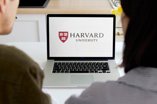 Students consulting harvard university website on laptop