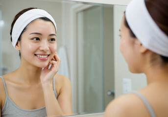 鏡の前でスキンケア後の肌の調子を確認する女性