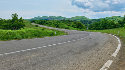 Scenic road winding through green fields and hills
