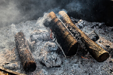 close-up of a campfire with hot embers and smoke surrounded by ash. lifestyles or safety design element