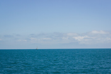 Obraz premium Minimalist shot of a single sailboat on the deep blue Mediterranean Sea off the Amalfi Coast. The clear sky and expansive water evoke calm and escape. Perfect for travel, vacation, and minimalist desi
