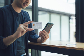 Man Holding Credit Card and Using Smartphone